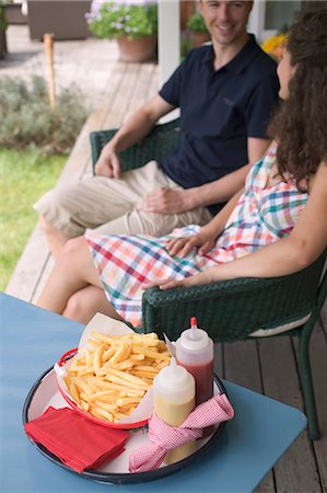 french fry smile - Couple sitting on terrace, chips in foreground Stock Photo - Premium Royalty-Free, Code: 659-06184438
