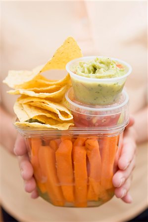 Woman holding plastic containers of vegetables & dips & nachos Stock Photo - Premium Royalty-Free, Code: 659-06184449