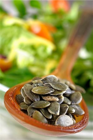 pumpkin seeds nutrition - Pumpkin seeds on a spoon in from of a bowl of salad Stock Photo - Premium Royalty-Free, Code: 659-06184909