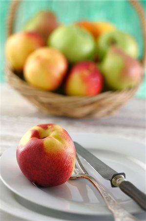 simsearch:659-06184917,k - A nectarine on a plate in front of a fruit basket Foto de stock - Sin royalties Premium, Código: 659-06184918