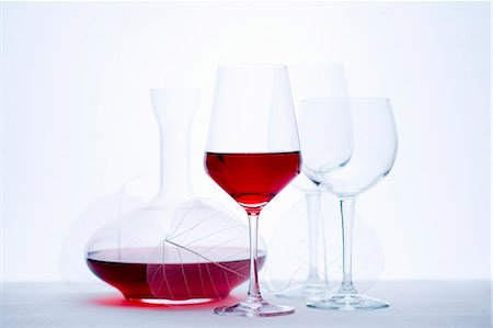 Glass of red wine, carafe and empty wine glasses Stock Photo - Premium Royalty-Free, Code: 659-06185001