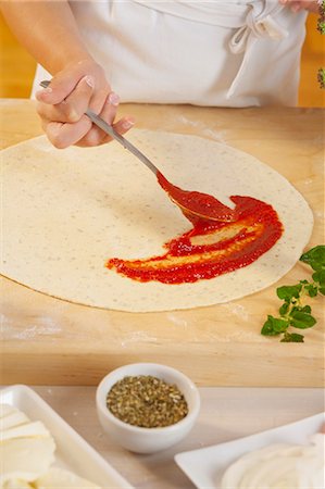 Girl spreading tomato sauce on pizza base Stock Photo - Premium Royalty-Free, Code: 659-06185376