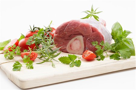 Jarret de veau aux herbes et tomates sur une planche à découper Photographie de stock - Premium Libres de Droits, Code: 659-06185778
