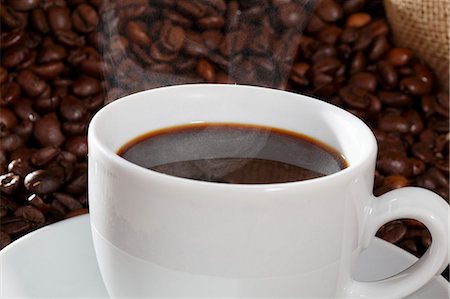 steaming coffee mug - A cup of coffee against a backdrop of coffee beans Stock Photo - Premium Royalty-Free, Code: 659-06185975