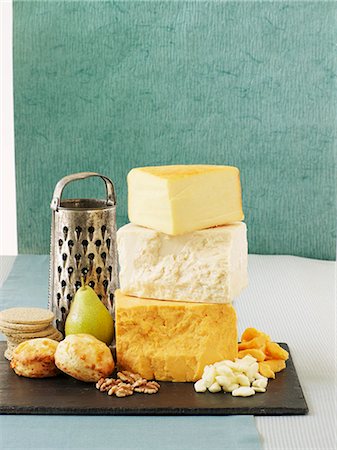 Parmesan Cheese and Grater Above. an above view of a block wedge of  parmesan cheese with shredded pieces all around and a metal cheese grater  on a cutting board Stock Photo