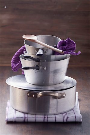 Stack of pots, a wooden spoon and a pot holder Stock Photo - Premium Royalty-Free, Code: 659-06186349
