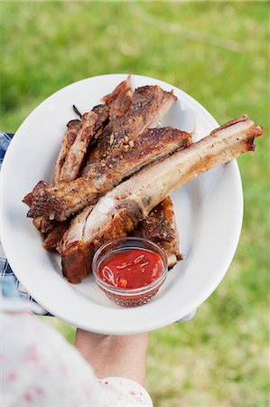 puerco - person holding a plate of grilled spare ribs and barbecue sauce Foto de stock - Sin royalties Premium, Código: 659-06186387