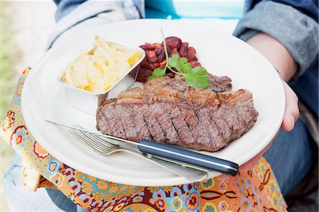 A person holding a plate of grilled beefsteak Stock Photo - Premium Royalty-Free, Code: 659-06186390