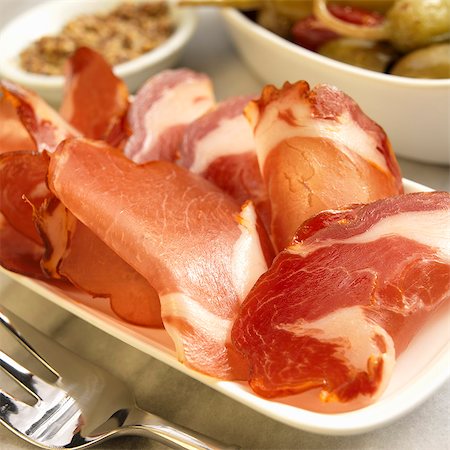 Slices of Dried Cured Spanish Pork Loin on a Platter; Peppers and Olives Stock Photo - Premium Royalty-Free, Code: 659-06186462