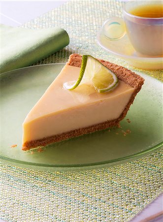 Slice of Key Lime Pie on a Green Plate; Cup of Tea Foto de stock - Sin royalties Premium, Código: 659-06186683