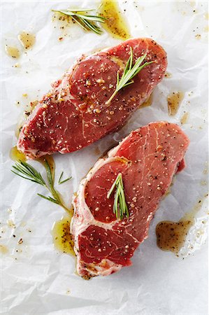 fleisch - Zwei rohen Steaks mit der Marinade und Rosmarin auf Metzgerei-Papier Stockbilder - Premium RF Lizenzfrei, Bildnummer: 659-06187784