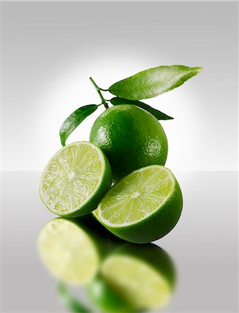 Two lime halves in front of a whole lime Foto de stock - Royalty Free Premium, Número: 659-06187805