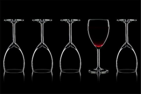 Row of wine glasses and a glass of red wine against a black background Stock Photo - Premium Royalty-Free, Code: 659-06187995