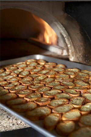 Baked Baguette Slices on a Sheet Pan Coming Out of a Pizza Oven Stock Photo - Premium Royalty-Free, Code: 659-06188167