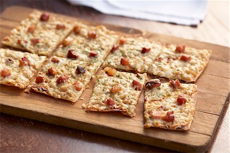 party recipe - Flat Bread Pizza with Bacon; Cut Into Squares on a Cutting Board Stock Photo - Premium Royalty-Free, Code: 659-06188161