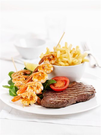 simsearch:659-01862823,k - Surf and Turf (beef steak and a prawn kebab) with chips Foto de stock - Sin royalties Premium, Código: 659-06183954