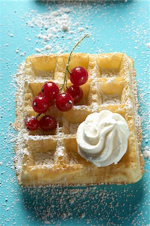 Une gaufre garnie de groseilles rouges, une cuillerée de crème et de sucre à glacer Photographie de stock - Premium Libres de Droits, Code: 659-06306578