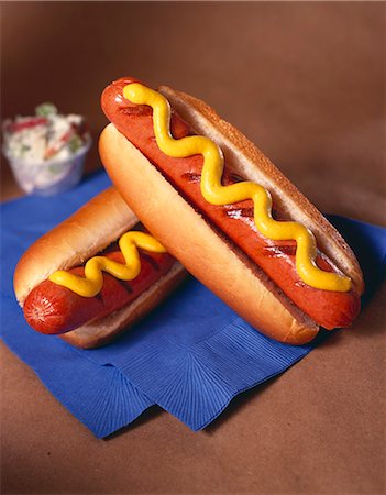 perro caliente - Two Grilled Hot Dogs on Buns with Mustard; On Blue Napkin; Cole Slaw Foto de stock - Sin royalties Premium, Código: 659-06307039