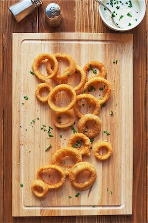Oven Baked Onion Rings Sprinkled with Parsley and Salt on a Cutting Board; Bowl of Blue Cheese Dressing Foto de stock - Sin royalties Premium, Código: 659-06307244