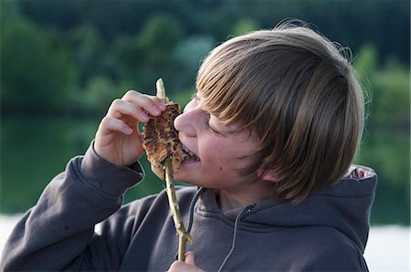 A boy eating stick bread Stock Photo - Premium Royalty-Free, Code: 659-06307249