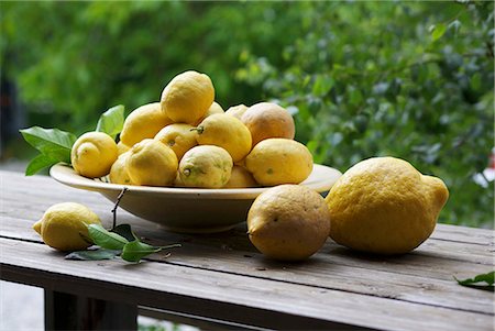 Lemons in a bowl on a wooden bench in the open air Foto de stock - Sin royalties Premium, Código: 659-06307262