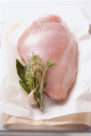 pavo (alimento) - Turkey breast with herbs and garlic cloves on a piece of paper Foto de stock - Sin royalties Premium, Código: 659-06307485