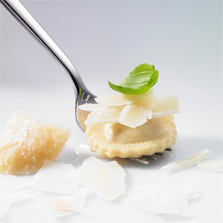 Ravioli, grated Parmesan and basil leaf on a fork Stock Photo - Premium Royalty-Free, Code: 659-06307618