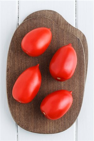 Four plum tomatoes on a chopping board Foto de stock - Sin royalties Premium, Código: 659-06372597