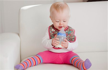 A baby sitting on a sofa with a bottle of milk Stock Photo - Premium Royalty-Free, Code: 659-06373079
