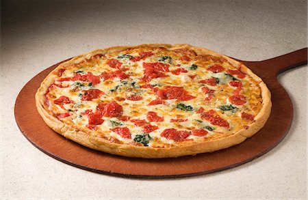 simsearch:659-06155632,k - Whole Tomato and Spinach Pizza on a Pizza Paddle Foto de stock - Royalty Free Premium, Número: 659-06373093