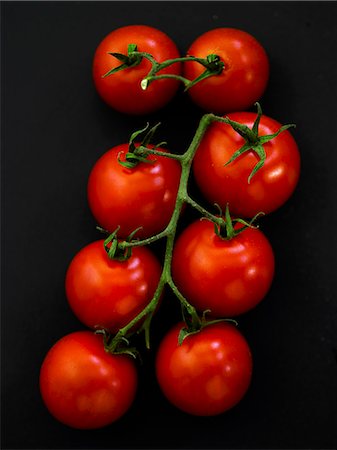 Vine tomatoes on a black surface Stock Photo - Premium Royalty-Free, Code: 659-06373376