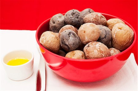 A bowl of jacket potatoes and a dish of butter Stock Photo - Premium Royalty-Free, Code: 659-06373387