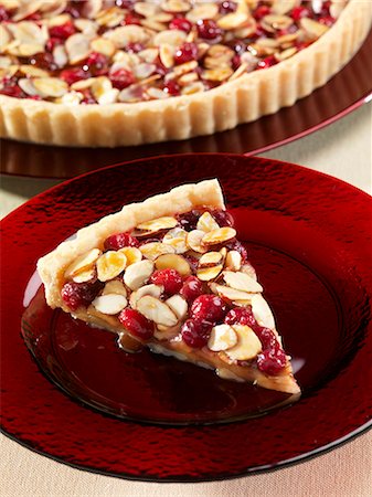 shortcrust pastry base - Slice of Cranberry Almond Caramel Tart; Whole Tart in the Background Foto de stock - Sin royalties Premium, Código: 659-06373400