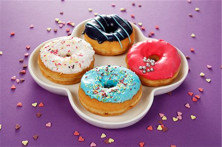 simsearch:659-06373902,k - Four doughnuts with colourful glaze and sugar sprinkles Foto de stock - Sin royalties Premium, Código: 659-06373521