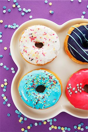 pastry on a plate - Four doughnuts with colourful glaze and sugar sprinkles Stock Photo - Premium Royalty-Free, Code: 659-06373522