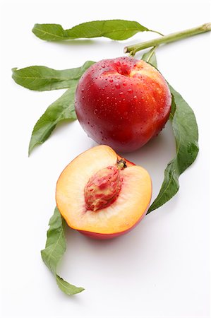 peach (fruit) - A whole nectarine and half a nectarine with leaves Foto de stock - Sin royalties Premium, Código: 659-06373612