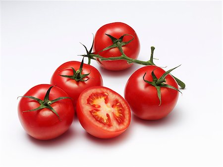 Four whole tomatoes and a halved tomato on a white surface Foto de stock - Sin royalties Premium, Código: 659-06373779