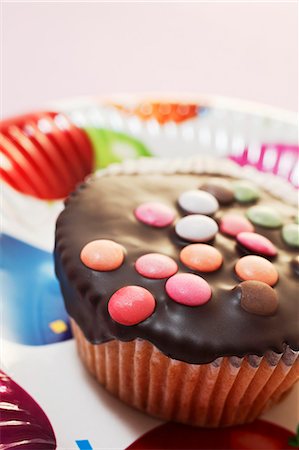 simsearch:659-06494038,k - A cupcake decorated with chocolate glaze and colourful chocolate beans Stock Photo - Premium Royalty-Free, Code: 659-06494036