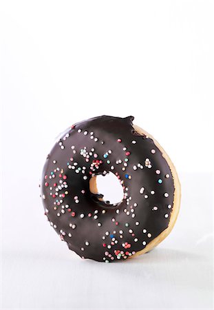 simsearch:659-01854280,k - A doughnut with chocolate glaze and colourful sugar sprinkles Foto de stock - Royalty Free Premium, Número: 659-06494095