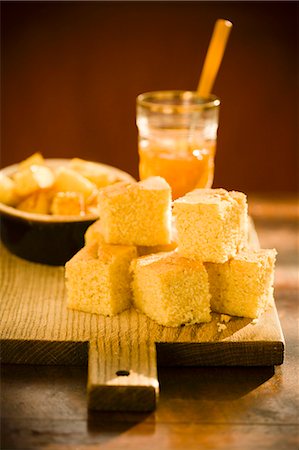 pão de milho - Pieces of Cornbread on a Cutting Board with a Jar of Jam Foto de stock - Royalty Free Premium, Número: 659-06494335