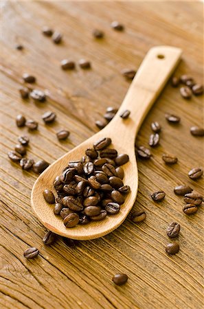 Roasted coffee beans on a wooden spoon and on a wooden surface Stock Photo - Premium Royalty-Free, Code: 659-06494489