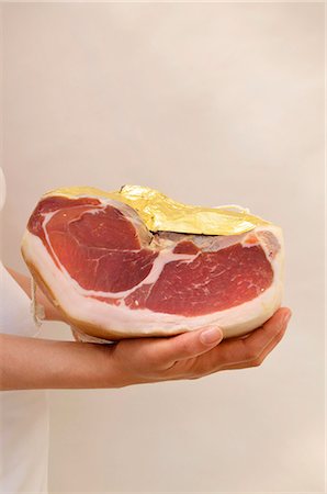 delicatessen - A woman holding a Parma ham wrapped in gold foil Foto de stock - Sin royalties Premium, Código: 659-06494988