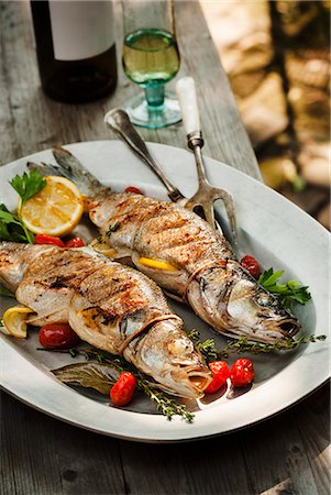 Two Whole Grilled Stuffed Branzino Fish on a Platter; On an Outdoor Table Photographie de stock - Premium Libres de Droits, Code: 659-06495114