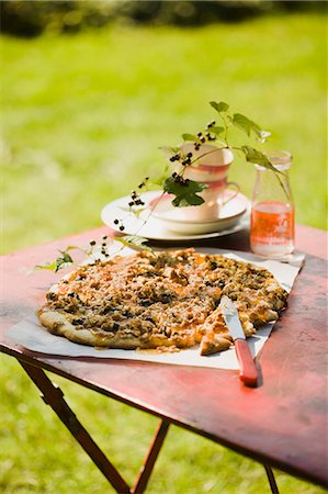 Peach Jam Pizza with Goat Cheese, Nuts and Blueberries; On an Outdoor Table; Blueberry Branch in a Bottle Stock Photo - Premium Royalty-Free, Code: 659-06671019