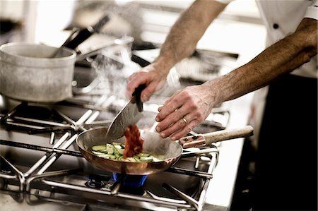 simsearch:659-01858152,k - A chef adding chopped tomatoes to a pan of courgette Photographie de stock - Premium Libres de Droits, Code: 659-06671145