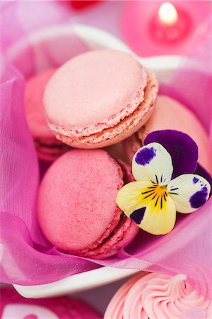 Strawberry and raspberry macaroons in a heart-shaped dish with a pansy Stock Photo - Premium Royalty-Free, Code: 659-06671403