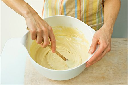 A woman mixes batter with a wooden spoon in a bowl Foto de stock - Sin royalties Premium, Código: 659-06671416