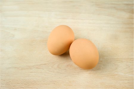 Two fresh eggs on a wooden surface Fotografie stock - Premium Royalty-Free, Codice: 659-06671417