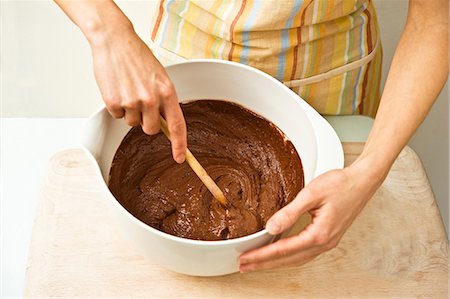 simsearch:659-07027825,k - A woman stirs chocolate cake mixture with a wooden spoon in a bowl Foto de stock - Sin royalties Premium, Código: 659-06671419