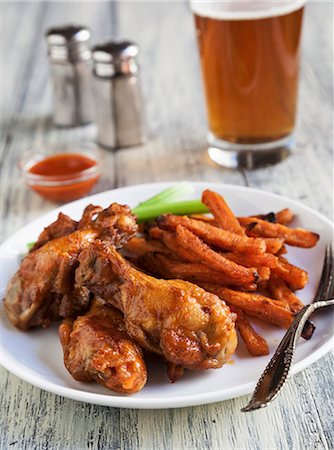 poule - Buffalo Chicken Wings with Sweet Potatoes Fries, Celery Sticks and a Glass of Beer Foto de stock - Sin royalties Premium, Código: 659-06671550